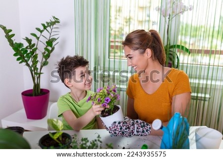 Mom and boy child water the plants together, Mom's little gardener assistant, taking care of children and flowers. Cute boy watering from watering can, take care of trees and plants, wet child