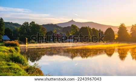 Idyllic sunny and hazy morning at the water. Chrastna pond, Czech: Chrastensky rybnik, and Jested mountain on background. Czech Republic