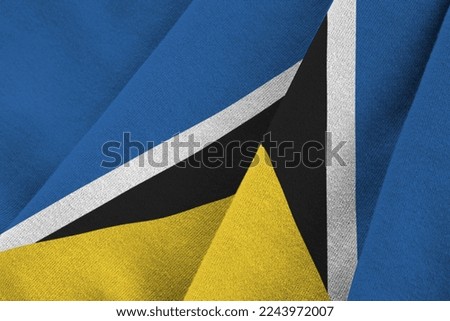 Saint Lucia flag with big folds waving close up under the studio light indoors. The official symbols and colors in fabric banner
