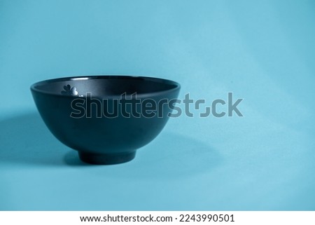 A black bowl with a floral pattern on a blue background