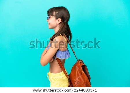Little caucasian kid going to the beach isolated on blue background in lateral position