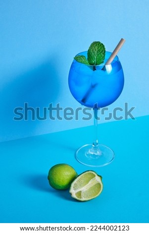 blue cocktail glass with lime and mint on blue minimalistic background