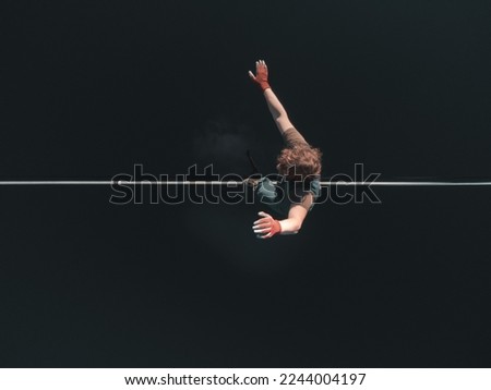 A tightrope walker walks along a line above the water. extreme sports Royalty-Free Stock Photo #2244004197