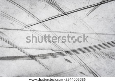 Textured background of vehicle traces on road from scooter, bike, bicycle weel. Tire print texture of transport Royalty-Free Stock Photo #2244005385