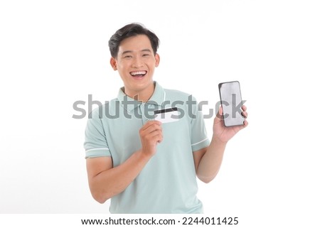 Portrait photo of a young handsome man, holding a credit card, paying online for the bills, isolated on white background