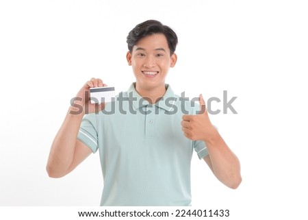 Portrait photo of a young handsome man, holding a credit card, paying online for the bills, isolated on white background