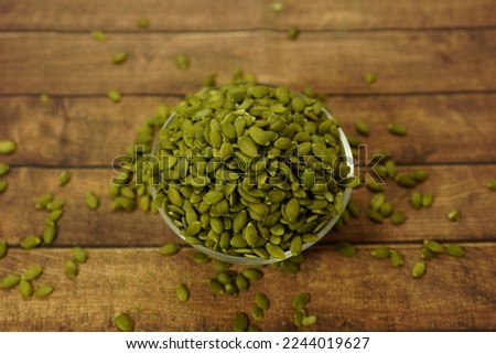 Raw unsalted pumpkin seeds, pepitas seeds with wood background