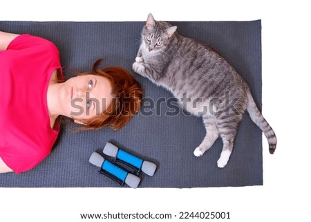 A tired woman and a cat lie on a training mat after a sports workout, isolated on a white background. Concept of isolation during the coronavirus epidemic and sports training