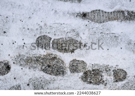 Footprints from shoes on white snow lying on the road, asphalt in the city in cold winter. Photography, texture.