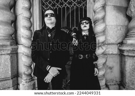 Stylish dark gothic couple in large ancient abandoned mausoleum with neoclassical style in a sunny day (in black and white)
