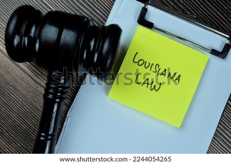 Concept of Louisiana Law write on sticky notes with gavel isolated on Wooden Table.