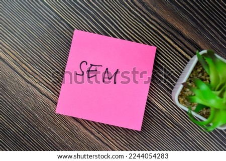 Concept of SEM write on sticky notes isolated on Wooden Table.