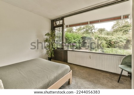 a bedroom with a bed, chair and large window looking out onto the trees that line the outside area in the room