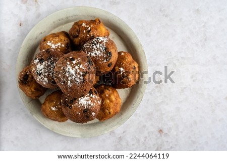 Top down view of a stack of tasty oliebollen (translation: Dutch dough fritters) with a glass of champagne on white background with copyspace on the right, horizontal