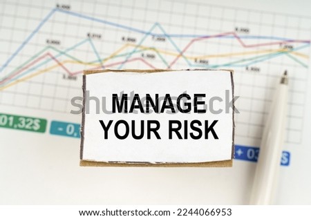 Business concept. Against the background of business graphics and pens, a sign with the inscription - Manage Your Risk