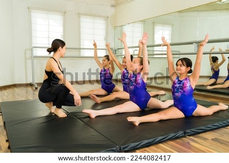 Cheerful girls gymnasts looking happy while doing a leg split during their gymnastics practice
