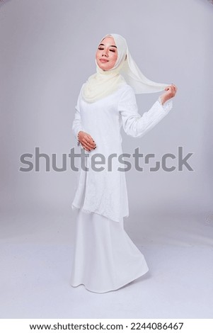 Fashionable young woman in long sleeves with hijab isolated over plain background. Stylish Muslim female hijab fashion lifestyle concept.