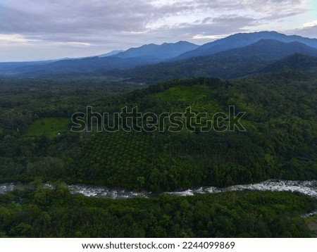Beautiful morning view of Indonesia. Aerial photo of a river between the mountains and forests of Indonesia