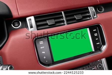 Monitor in car with isolated blank screen use for navigation maps and GPS. Isolated green screen with chroma key. Car display with blank green screen. Modern car red leather interior 