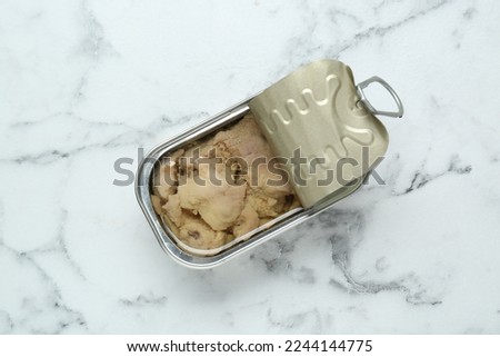 Open tin can of tasty cod liver on white marble table, top view