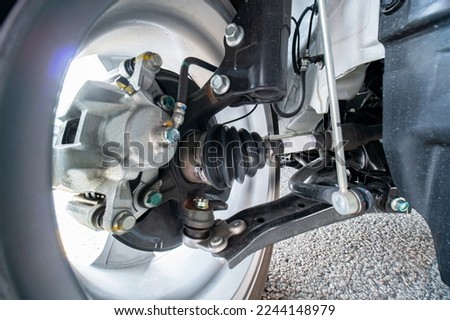 Close-up view of new CV Joint and rubber boot on the front car wheels. Part of suspension system components, including CV axles and half shaft assembly, strut, steering knuckle, control arm bushing.  Royalty-Free Stock Photo #2244148979