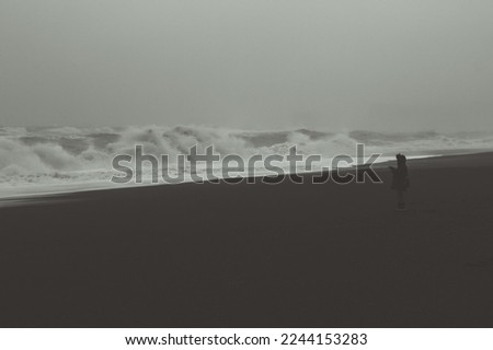 Person at stormy seaside monochrome landscape photo. Beautiful nature scenery photography with sky on background. Idyllic scene. High quality picture for wallpaper, travel blog, magazine, article