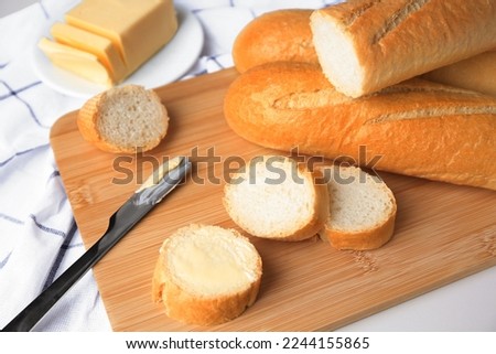 Tasty cut baguette with fresh butter on white table