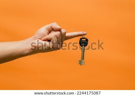 Man's hand with keys isolated on orange background