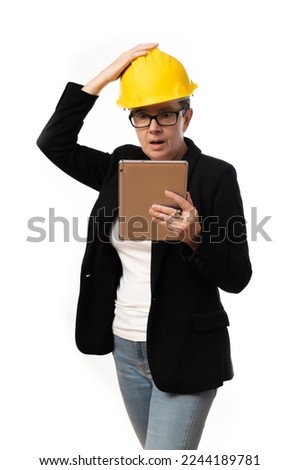 business woman in suit and yellow helmet teleworking using technology, consulting her tablet gesturing on black background