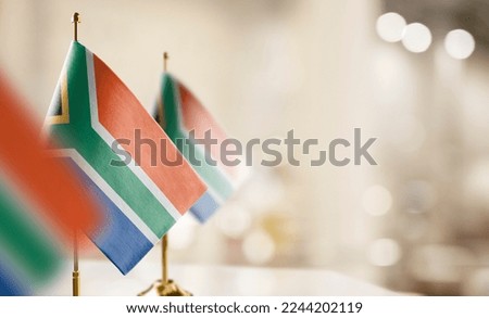 Small flags of the South Africa on an abstract blurry background.