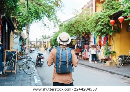 happy Solo traveler sightseeing at Hoi An ancient town in central Vietnam, man traveling with backpack and hat. landmark and popular for tourist attractions. Vietnam and Southeast Asia travel concept Royalty-Free Stock Photo #2244204559