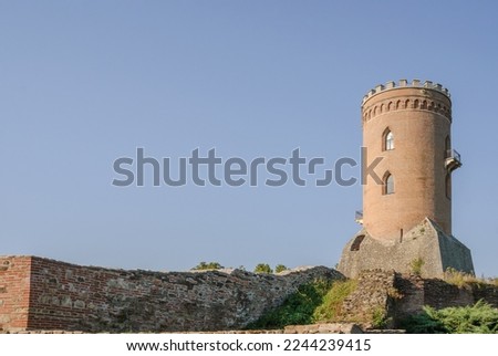 Medieval old brick tower of castle. Medieval building. Tower of ancient castle with opened windows. Historic architectural element on blue sky background.