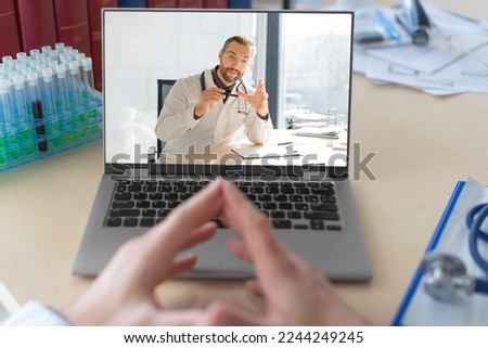 Photo of a doctor in front of a laptop monitor during an online video call. Conversation with a colleague. Online conversation.