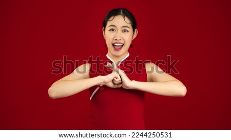 Chinese woman in red dress posing respecting, smiling and greeting on red color backgroun to celebrate Chinese New Year.