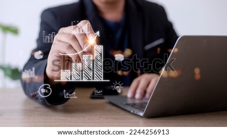Businessman draws an increasing trend arrow and a rising chart from plan to goal. It is a representation of the idea of corporate investment development. Royalty-Free Stock Photo #2244256913