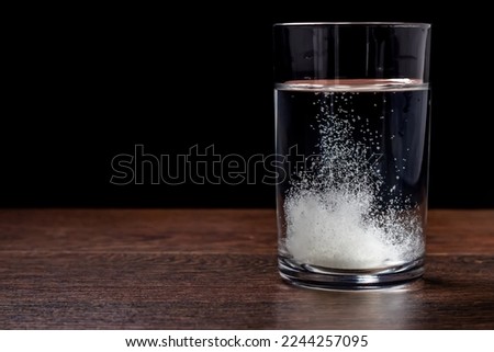 Effervescent tablet in a glass of water close-up on a black background. The concept of health