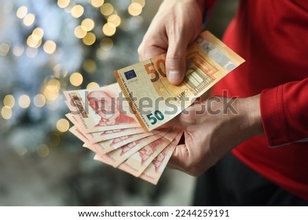 Man hand holding 50 euros with pile of Serbian dinar paper currency, 1000 dinars behind Royalty-Free Stock Photo #2244259191