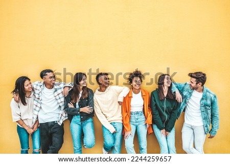 Happy multiracial friends standing over isolated background - Cheerful young people socializing outdoors - University students laughing together on yellow wall - Youth culture and friendship concept Royalty-Free Stock Photo #2244259657