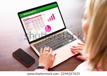 Woman working on spreadsheets on laptop Royalty-Free Stock Photo #2244267633