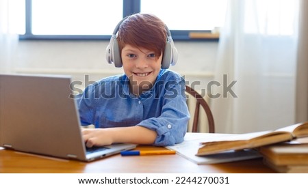 Photo of a red-haired boy during an online video call with friends. He writes messages and communicates online.