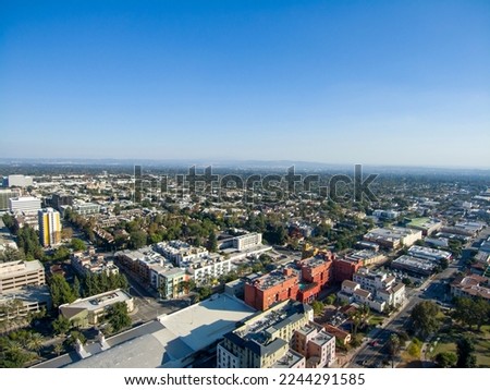 an aerial shot of the apartments, shops and office buildings in the city skyline with mountains and cars driving on the street, lush green trees and a clear blue sky in Pasadena California USA Royalty-Free Stock Photo #2244291585