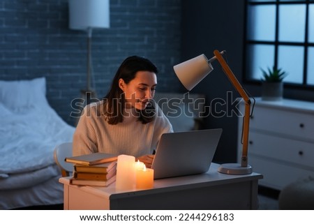 Young woman using laptop at home during blackout Royalty-Free Stock Photo #2244296183