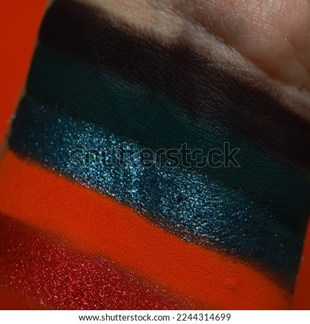 Eye shadow swatches, dry powder, set of dark red and blue multichrome metallic brush strokes on skin. Cosmetic makeup texture samples, smear trace samples on pink background. Realistic photography