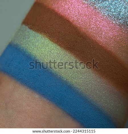 Eye shadow swatches, dry powder, set of multicolor matte multichrome metallic brush strokes on skin. Cosmetic makeup texture samples, smear trace samples on pink background. Realistic photography
