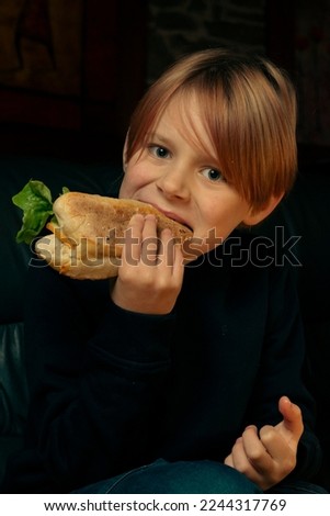 9 year old boy eating a big baguette sandwich