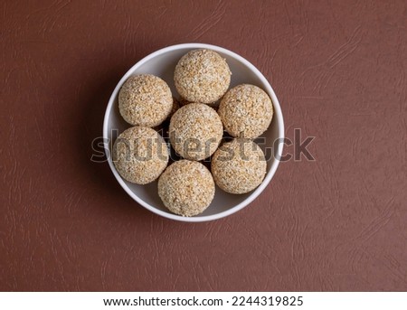 The indian sesame sweet or tilgul laddu, made up of jaggery and sesame seeds, indian sweet for Makar Sankranti festival, pile or stacked on black background, closeup showing texture, selective focus Royalty-Free Stock Photo #2244319825