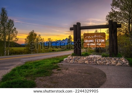 Welcome sign at the entrance to Grand Teton National Park in Wyoming, with Teton Mountain Range in the background. Photographed at sunset. Royalty-Free Stock Photo #2244329905