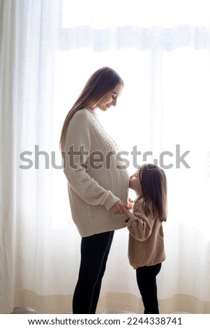 Little girl kissing her pregnant moms belly
