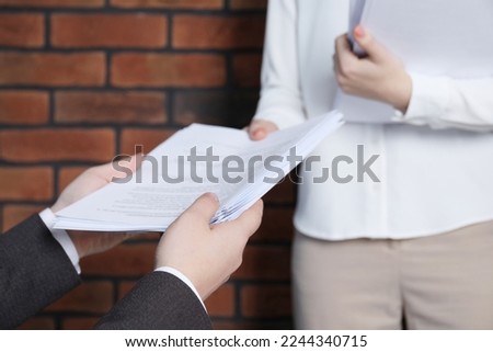 Woman giving many documents to man in office, closeup