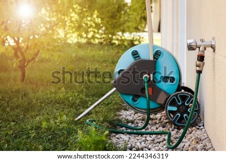 Hose with Faucet Outdoor for Watering. Lawn Sprinkler attached to Mobile Garden Hose Reel and Brass Tap Outside. Royalty-Free Stock Photo #2244346319